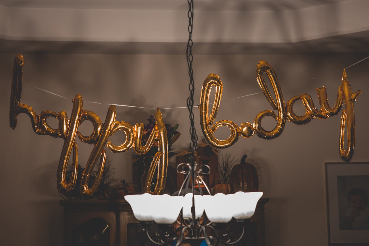 Festive gold balloons spelling happy bday hang indoors, ideal for party themes.